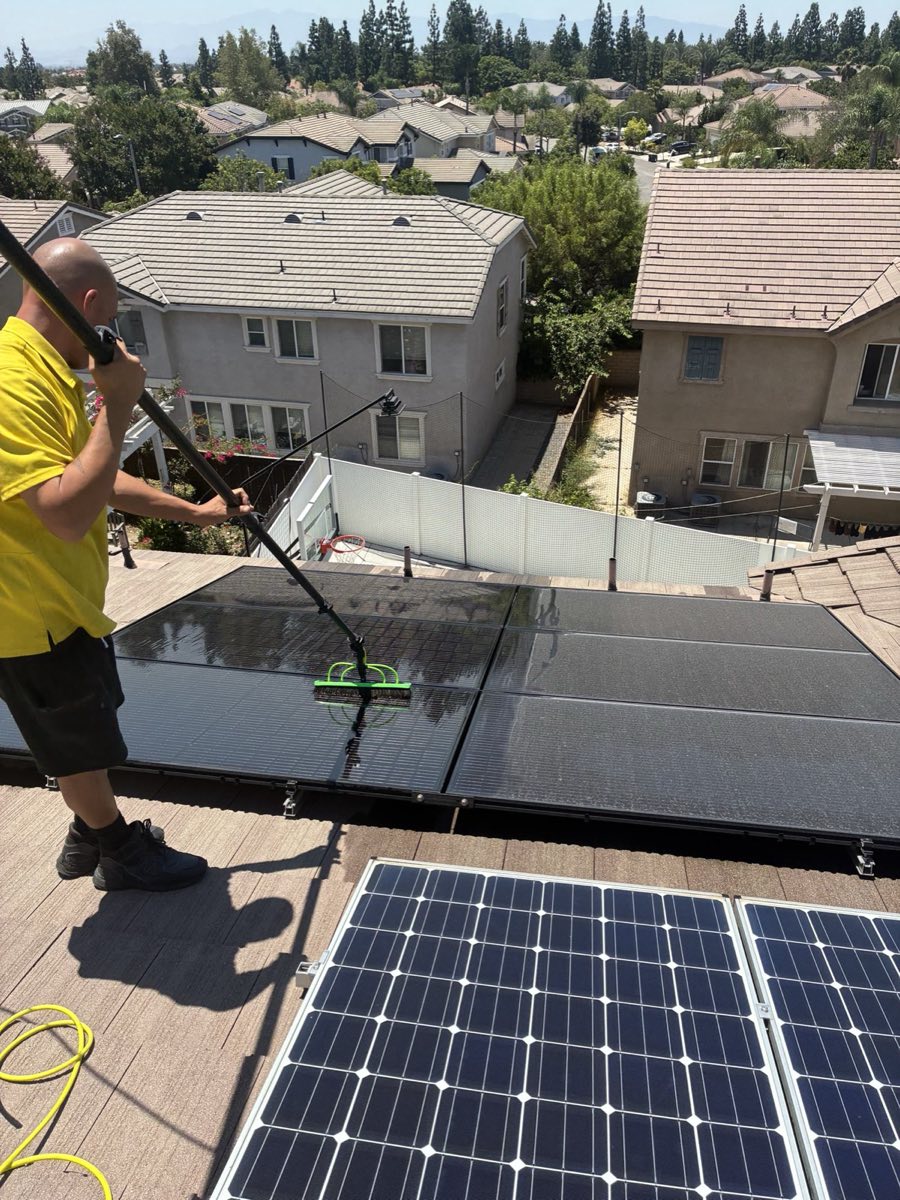 Technician cleaning rooftop solar panels